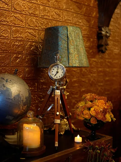 Details matter in a speakeasy. A vintage-style tripod clock lamp sits beside a globe and candles, adding to the curated, old-world feel of the space.