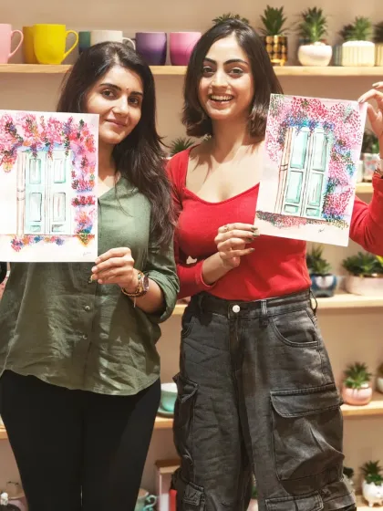 Two women happily display the beautiful watercolor paintings they made in a beginner art class at my Pune studio, perfect for anyone wanting to start their creative journey.