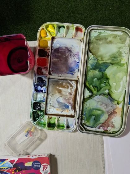 An artist's watercolor palette after a painting session. The beautiful mess of mixed colors tells a story of the creative process.