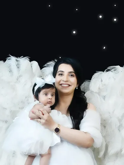 A magical portrait of a mother and her baby, both dressed in white with large angel wings against a starry night backdrop. This is a beautiful concept for a mother-child photoshoot.