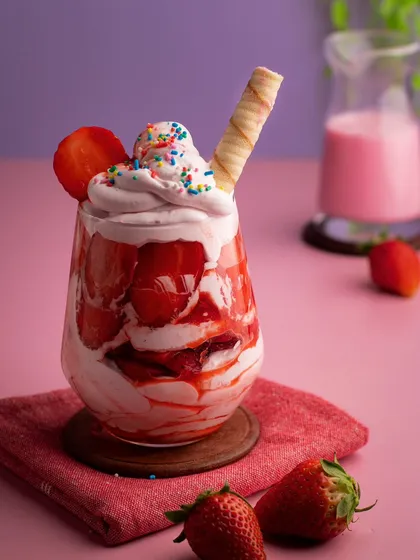 A glass of fresh strawberry cream. The layers of red strawberries and white cream create a beautiful and tempting dessert.