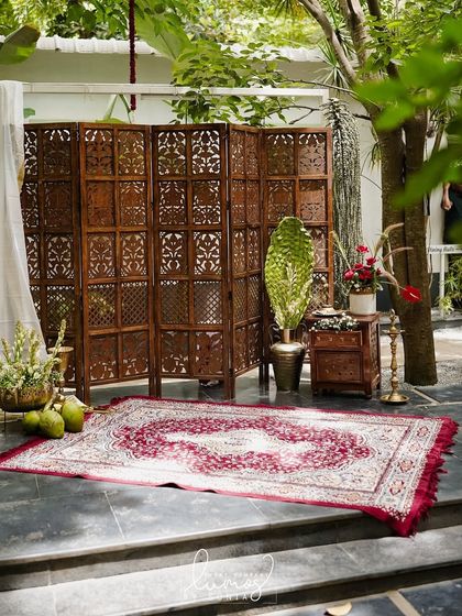 A charming selfie booth with a vintage vibe, featuring a teak wood screen, a traditional rug, and authentic Kerala decor elements.