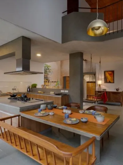 The heart of this home is an open-plan area where the kitchen island seamlessly extends to become the dining table. This design encourages family interaction and is flanked by views of an indoor courtyard and garden, blurring the lines between cooking, dining, and living.