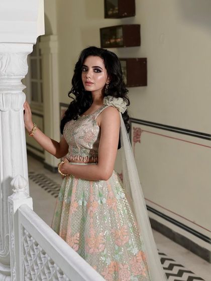 A close-up of the floral embroidered lehenga, showing the intricate details of the blouse and the one-shoulder cape. The craftsmanship is evident in every stitch.