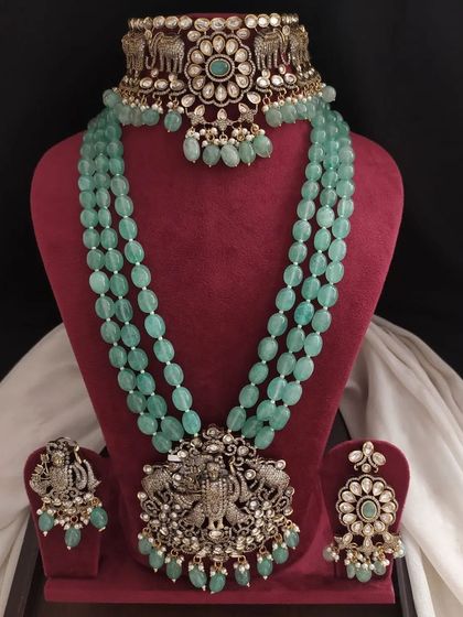 A beautiful Victorian set in pastel green, featuring an elephant motif choker and a long beaded necklace with a large deity pendant. The craftsmanship is exquisite.
