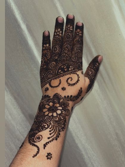 A close-up of a fresh Arabic henna design. You can see the clean lines and the combination of bold flowers with delicate swirls and dots.