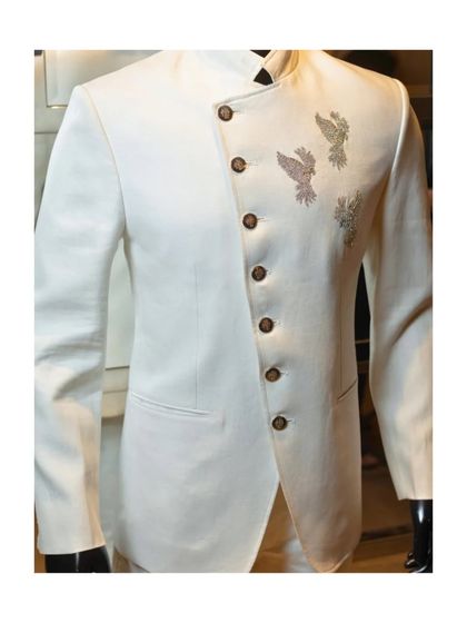 This unique white bandhgala features an asymmetric, overlapping front panel. The three hand-embellished birds add a touch of artistry, making it a modern and elegant choice.