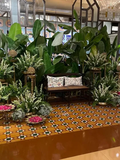 A traditional and elegant seating area for a baby shower. We used lush green banana leaves, white rajnigandha flowers, and brass elements to create a serene and classic Indian decor theme.