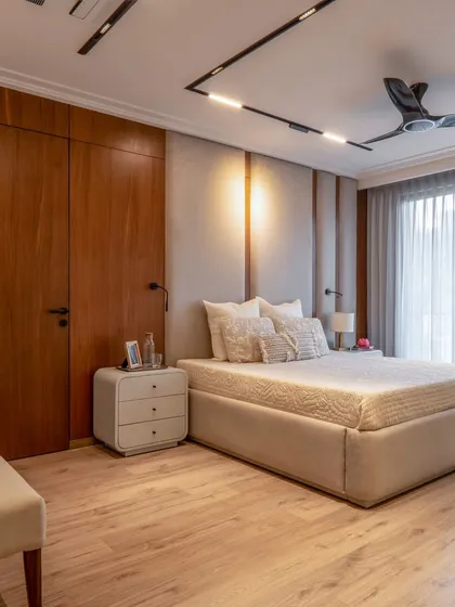A beautiful blend of wood and fabric textures in this minimalist bedroom. The track lighting on the ceiling is a modern touch, while the wooden wardrobe and flooring add warmth and a natural feel.
