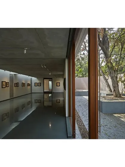 A view from the subterranean gallery at the Kasturbhai Lalbhai Museum. A large glass wall opens the underground space to a sunken courtyard, bringing in natural light and connecting the gallery to the landscape above.