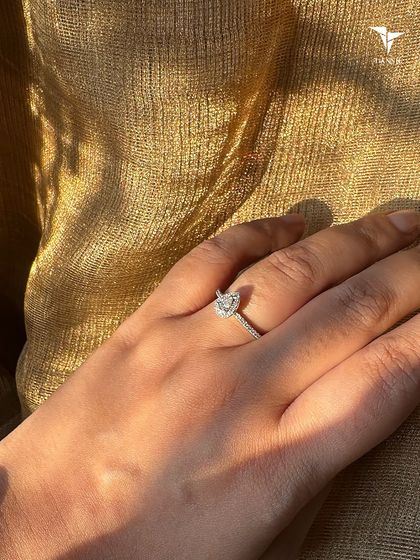 A delicate pear shaped diamond solitaire ring, shown in the warm glow of the sun. This design offers a unique and elegant alternative to a traditional round cut.