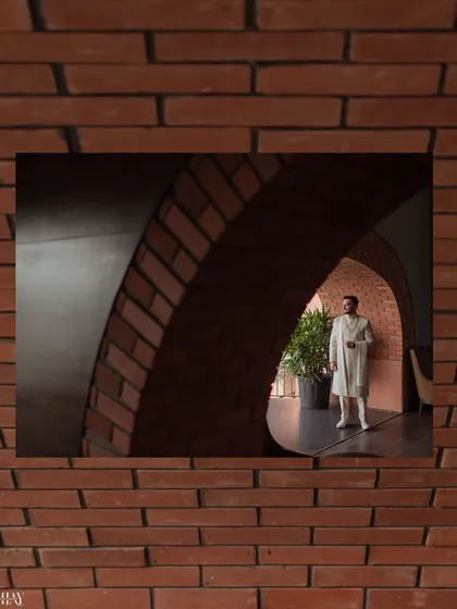 A creatively framed shot of the groom seen through a brick archway. This composition uses architectural elements to create a sense of depth and focus, resulting in a unique and artistic groom portrait.