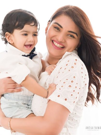 A mother holds her laughing son, her own smile radiating pure happiness. A beautiful, candid moment of motherly love.