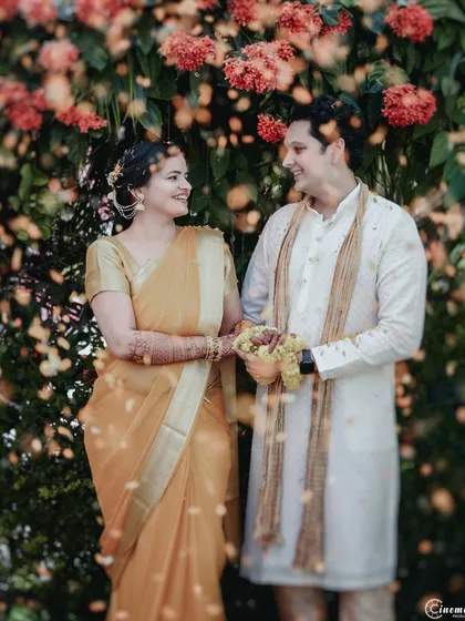 A happy couple portrait during their Haldi, with flower petals raining down around them. A perfect blend of candid joy and classic portraiture.