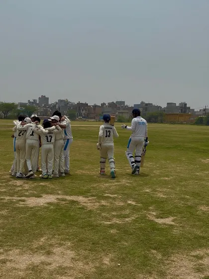 The team in a huddle, with the opening batsmen walking out. A picture of unity.
