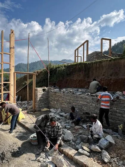 Local artisans carefully stacking stones for the foundation walls. This traditional building method requires immense skill and patience, and is fundamental to creating architecture that feels rooted in its location.