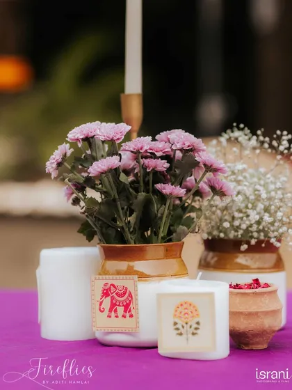 A close-up of a centerpiece from Devika and Harsh's event, featuring small clay pots and candles with custom block-print labels.