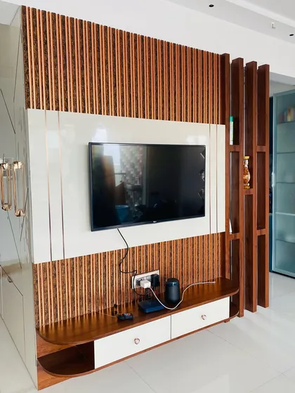 This TV unit uses vertical wooden flutes to create texture and warmth. It's paired with a sleek white console and a wooden partition that doubles as a display shelf, separating the living area without closing it off.