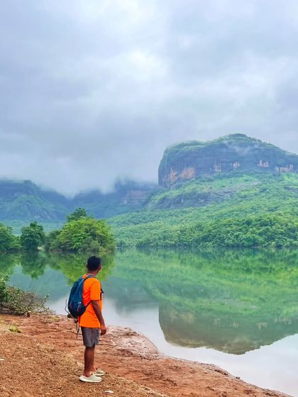 A moment of quiet reflection by a serene lake in Maharashtra, with the majestic mountains reflecting perfectly in the still water.