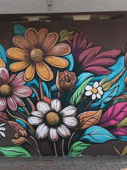 A vibrant, Pinterest-inspired floral mural painted on an exterior wall. The rich colors and bold flower designs completely transform a plain brown wall.