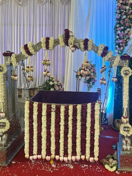A silver cradle decorated with vertical stripes of purple and white flowers, perfect for a traditional naming ceremony.