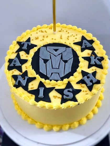 A simple buttercream birthday cake with a Transformers logo. This shows how to add custom fondant details to a classic piped cake.