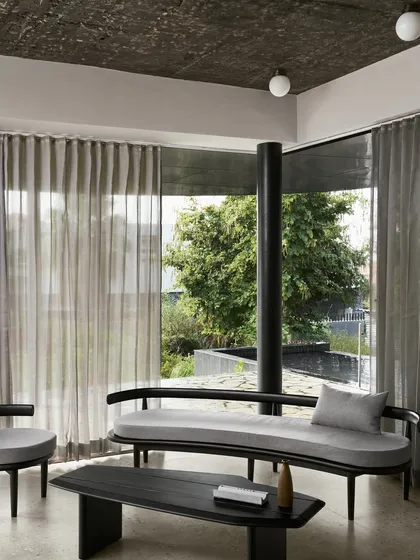 For the Pavilion House, we designed a serene retreat that merges with the landscape. This living area showcases our minimalist aesthetic, using a monochrome palette, curated black wood furniture, and expansive glass walls to create a tranquil space for contemplation and connection with nature.