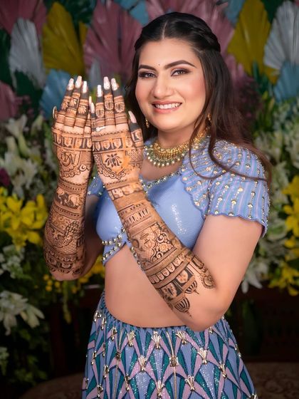 A happy bride showing off her intricate "architecture on skin" mehendi. Her smile is as bright as her beautiful outfit.