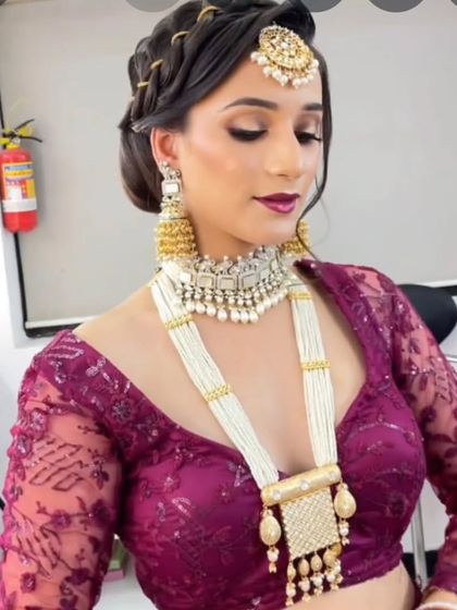 A model in a purple blouse wearing a layered pearl and Kundan set. This rani haar style adds a touch of royalty to any outfit.