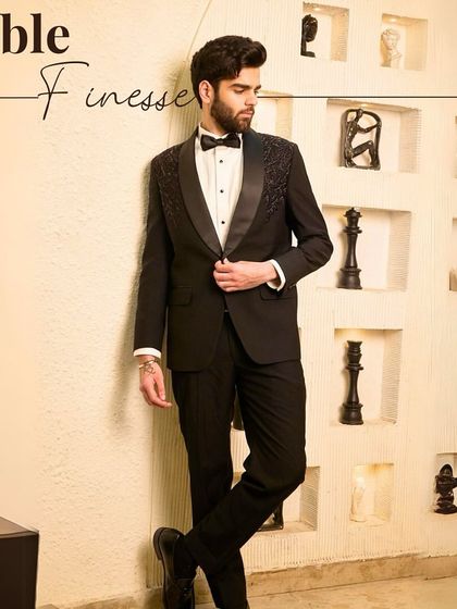 The epitome of noble finesse. This full-length view showcases a classic black tuxedo with embellished shoulders, styled to create a powerful and sophisticated silhouette for the modern gentleman.