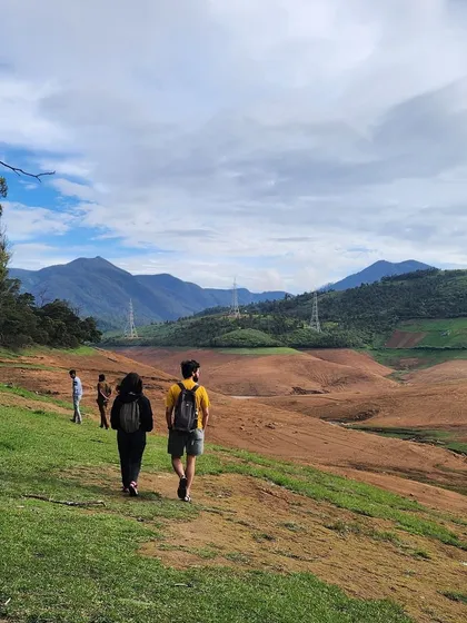 Trekkers walking along a path overlooking a vast valley. This captures the scale and beauty of the mountains we explore.
