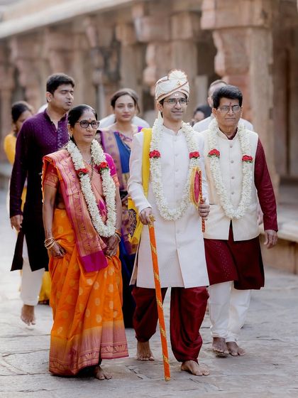 The groom's grand entrance, accompanied by his parents. This shot captures the pride and importance of family during the wedding procession.