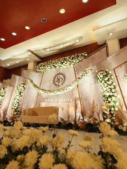A low-angle shot of our elegant white and gold reception stage, showcasing the beautiful foreground of white chrysanthemums. This perspective highlights the depth and scale of the floral arrangements we create.