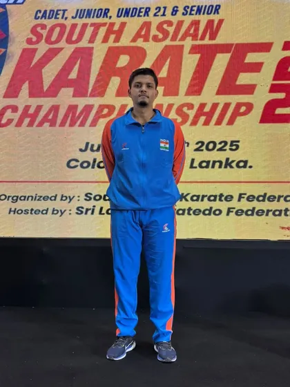 Jitendra Kumar standing in front of the official banner for the 9th South Asian Karate Championship, representing our academy with focus and pride.