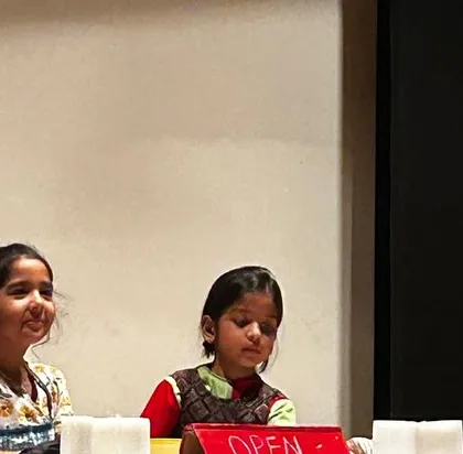 Two young actresses sharing a laugh at the props table. These candid moments show the fun and camaraderie of being in a play.