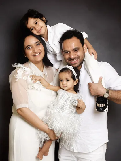 A classic studio family portrait with everyone dressed in white. The father holding his son on his shoulders adds a playful touch to this elegant shot.