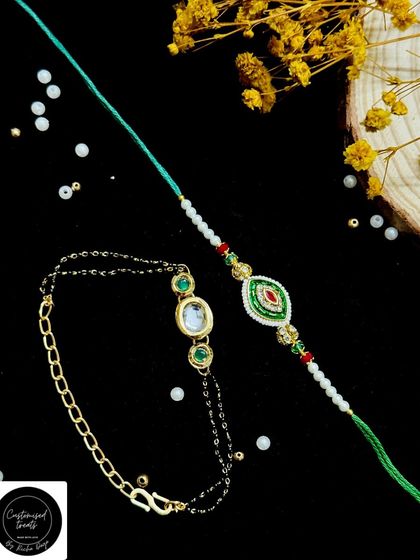 This unique Bhaiya-Bhabhi set features a modern chain-link Lumba with a mangalsutra-style design, paired with a traditional thread rakhi with matching kundan work.