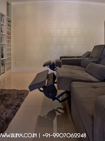 This living room setup features a large screen integrated into a custom media wall. The reclining sofa provides ultimate comfort, allowing the family to transition from a casual living area to an immersive movie watching environment with ease.