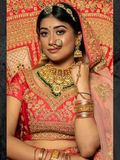 A classic North Indian bridal look with a red and gold lehenga. The makeup is kept warm and glowing to complement the rich colours of the outfit.
