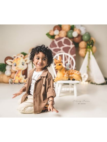 A happy little explorer in his safari-themed second birthday setup. His joyful smile is the highlight of the shot.