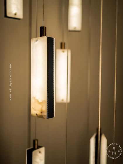 These modern pendants feature a unique combination of translucent marble and stitched leather accents. The warm light glows through the marble, creating a sophisticated and texturally rich fixture for contemporary spaces.