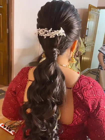 A Sangeet look featuring a wavy ponytail with a pearl accessory. It's a chic and comfortable style for a night of dancing.