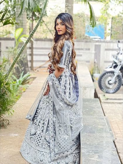 The back view of the grey lehenga, showing the beautiful long hair of the model and the way the sheer dupatta drapes over the detailed skirt.