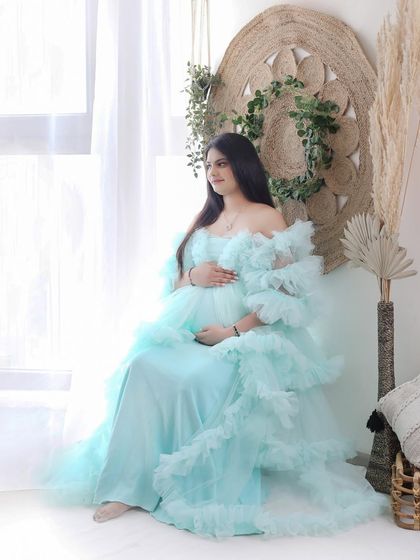Soft, dreamy, and ethereal. This mom-to-be looks serene in a light blue ruffled gown, posed near a window to capture the soft natural light.