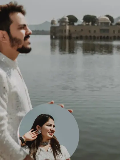 A creative and artistic portrait using a mirror to reflect the bride-to-be, while the groom looks out at the Jal Mahal. This shot plays with perception and adds a unique narrative layer.