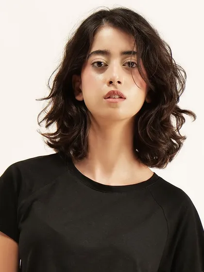 A close-up portrait shot that focuses on the model's expression while still keeping the texture of the black t-shirt visible.