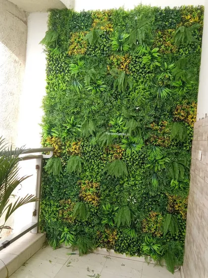 A dense artificial green wall installed on a residential balcony, providing privacy and a lush garden view without the need for soil or water.