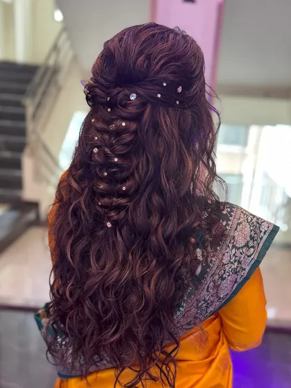 I love combining textures in my hairstyles. Here, I've created a half updo with a soft braid and flowing curls, accented with shimmering gems for a glamorous party look.