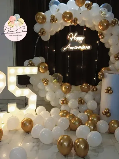 A beautiful 25th anniversary setup with a white and gold balloon ring, neon sign, and a large marquee number '25'.