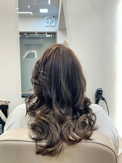 A back view of a client's hair after a color transformation. The deep, uniform color is styled into voluminous curls, adding depth and a touch of glamour.